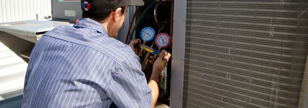 HVAC technician servicing a condenser unit in Kaneohe
